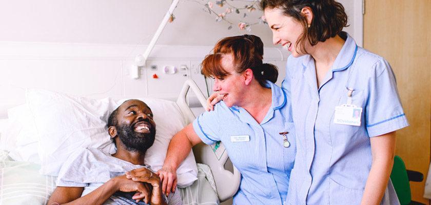 Uomo di colore che sorride a due infermiere – Glande arrossato