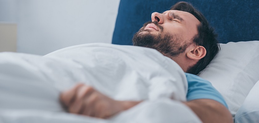 Uomo sdraiato a letto mentre stringe la coperta con le mani – Cattivo odore intimo uomo