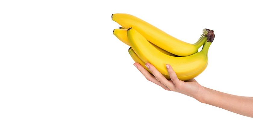 Vista di un braccio di ragazza dal lato destro mentre alza un paio di banane fresche